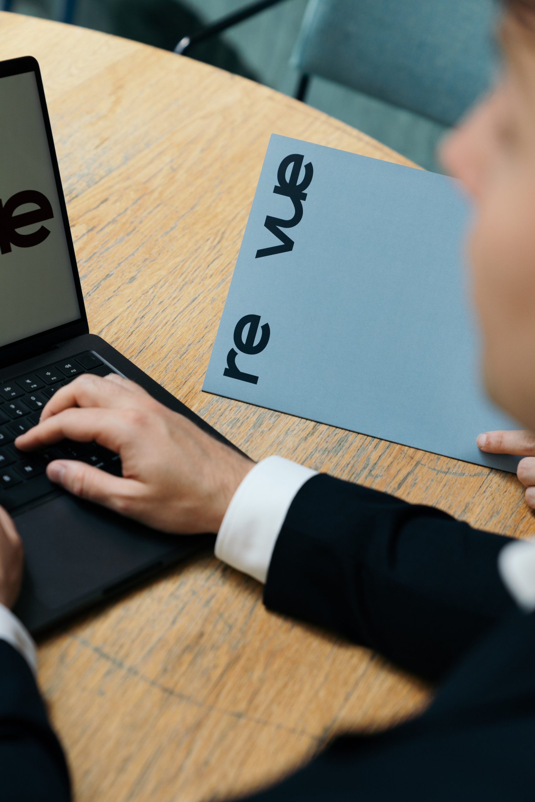 Vastgoedadviseur van Re Vue werkt op een laptop naast een Re Vue-brochure
